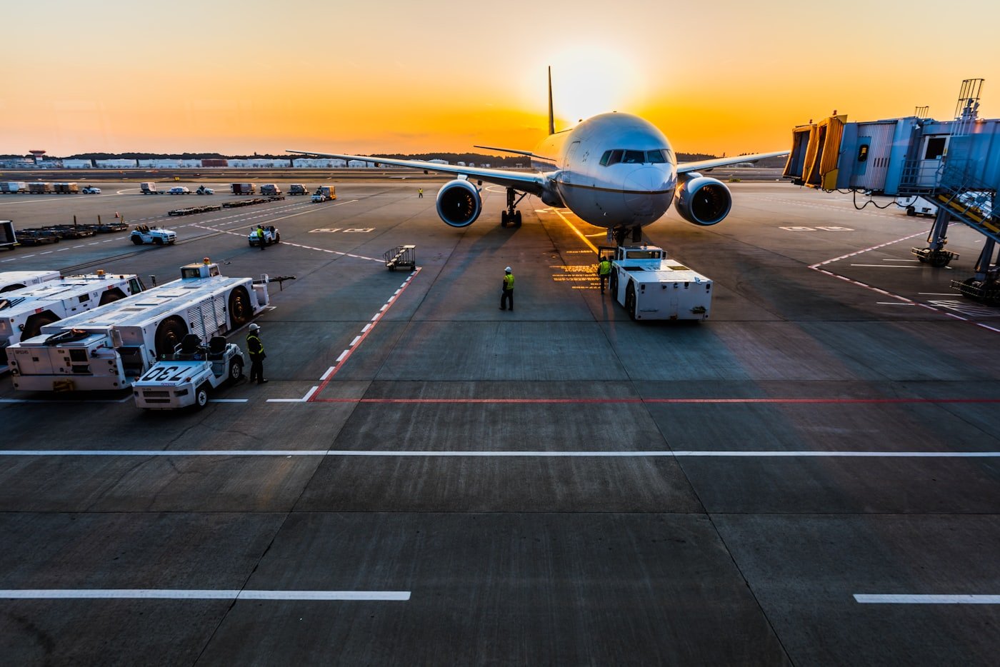 Wide-body aircraft at a Dubai airport gate at sunset - a 24/7 environment kept running by HVAC facilities teams